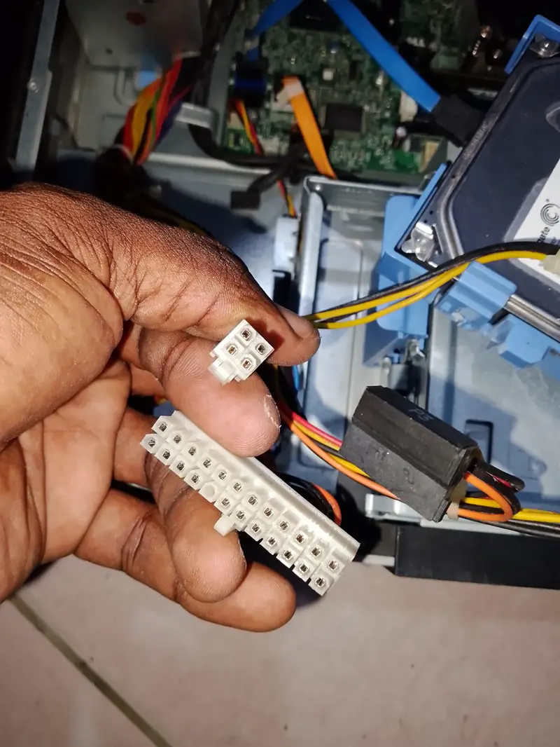 Connecteurs d'alimentation tenus en main devant une unité centrale ouverte
