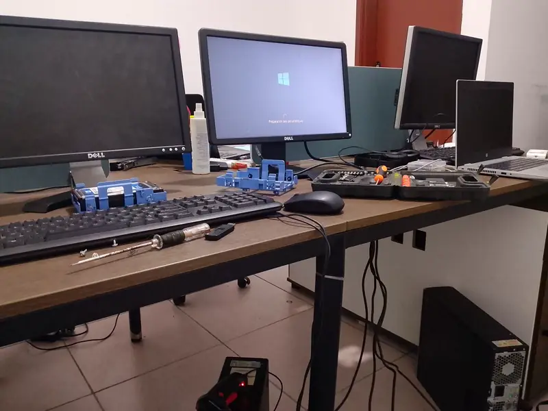 Bureau avec plusieurs écrans, claviers, disques et outils pendant la remise en état des postes